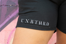 Load image into Gallery viewer, CLOSE UP OF EMBROIDERED LOGO ON RIGHT LEG. 100% COTTON UNISEX SHORTS BLACK. 
