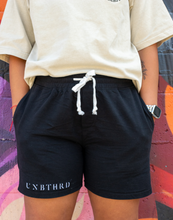 Load image into Gallery viewer, BLACK UNISEX 100% COTTON SHORTS. WHITE TIE STRINGS. EMBROIDERED LOGO ON RIGHT LEG. 
